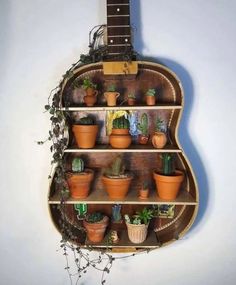 a guitar shaped shelf filled with potted plants