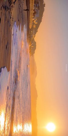 the sun shines brightly in front of an ice covered cliff on a foggy day