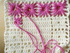 a close up of a piece of crocheted material with pink thread on it