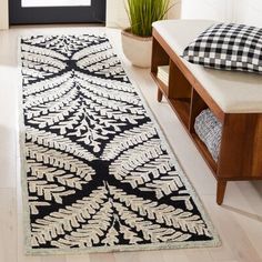 a black and white runner rug on the floor in front of a window with a potted plant next to it