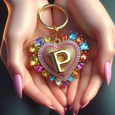 a woman's hands holding a heart shaped keychain with the letter p on it