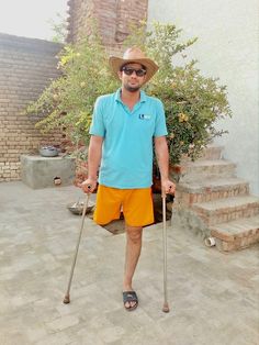 a man in blue shirt and yellow shorts holding two canes while standing next to steps