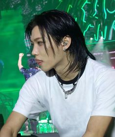 a man with black hair and piercings sitting in front of a laptop computer at a desk