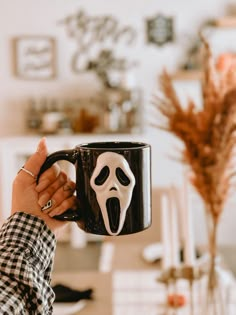 a person holding a coffee mug with a ghost face on it