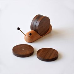 a wooden snail sitting on top of a white table next to two small round buttons