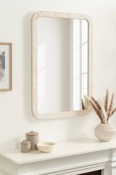 a white fireplace with a mirror on the mantle