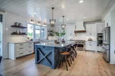 a large kitchen with white cabinets and wooden floors