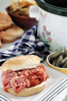 a sandwich on a plate with pickles and bread in the background