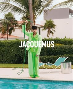 a man standing next to a swimming pool with a hose in his hand and the words jacquemus above him