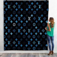 a woman is standing in front of a wall with blue louis vuitton pattern