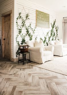 a living room with white couches and green plants growing on the wall behind them