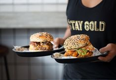 two people holding plates with sandwiches on them