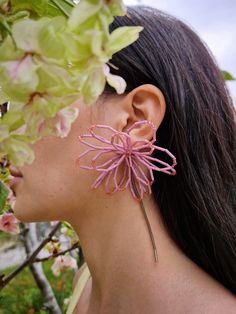 a close up of a person wearing ear clips with flowers in front of her face