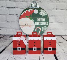 three red bags with santa clause on them sitting in front of a sign that says merry christmas