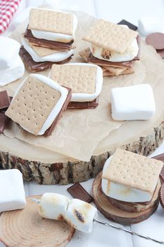 marshmallows and graham crackers are arranged on top of a piece of wood