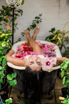 a woman laying down in a bathtub filled with flowers