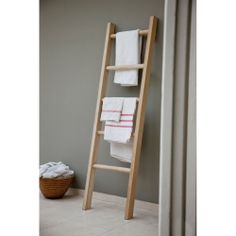 a wooden ladder leaning against a wall with towels on it