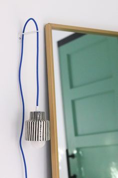 a light that is plugged in to a wall next to a mirror with a blue cord