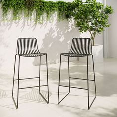 two black metal barstools sitting next to each other on a white tiled floor