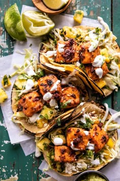 three shrimp tacos with lime wedges on the side