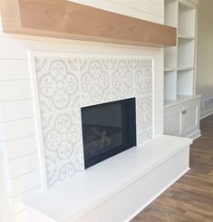 a fireplace in a living room with white walls and wood flooring on the other side