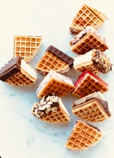 several waffles with chocolate, peanut butter and other toppings on them sitting on a marble surface