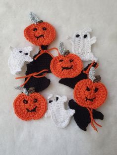 crocheted pumpkins and ghost decorations on a white surface