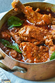 a pot filled with meat and sauce on top of a table cloth next to a spoon