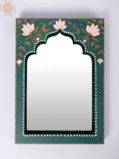 a mirror with flowers and leaves on the front, hanging on a wall above it