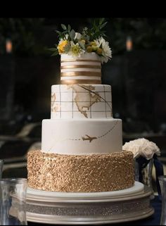 a three tiered wedding cake with gold and white decorations on it's side