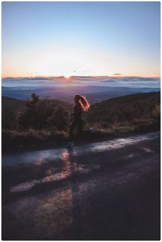 a woman standing on the side of a road at sunset