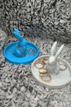 a rabbit figurine sitting on top of a table next to rings and ring holders