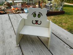 a white wooden chair with a cat face painted on it's head and eyes