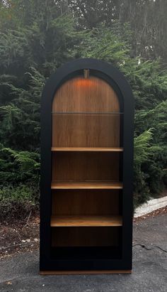 a wooden book case sitting in front of some trees