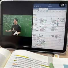 an open book sitting on top of a table next to a laptop computer and tablet