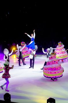 people are skating on an ice rink with large cakes in the shape of dresses and hats