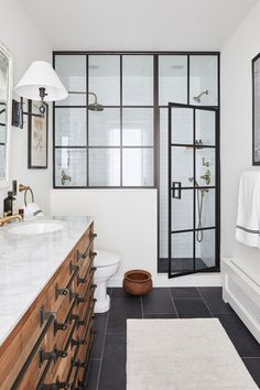 a bathroom with black and white tile flooring next to a walk in shower stall