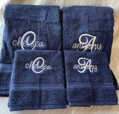 three towels with embroidered names on them sitting on a bed together, one is blue and the other has white lettering