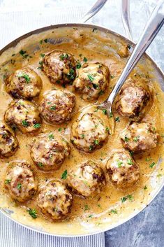 a white plate topped with meatballs covered in gravy next to a fork