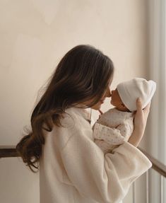 a woman holding a baby doll in her arms and looking out the window at something outside