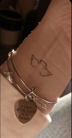 a woman's arm with a tattoo on it and a heart charm attached to the wrist