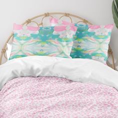 a bed with pink and green pillows on top of it next to a potted plant