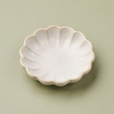 a small white bowl sitting on top of a table next to a green wall,