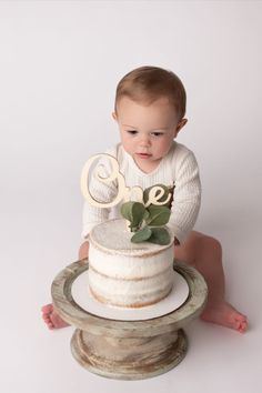 a baby is sitting on the floor with a cake in front of him that says love