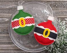 two decorated christmas ornaments sitting on top of a glass plate