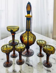 a table topped with lots of glass vases and candlesticks on top of a marble counter