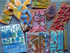 several different designs and shapes are displayed on a table with blue, green, red, orange, and yellow paper