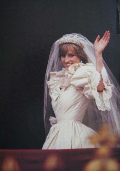 a woman in a wedding dress waves to the crowd while standing next to her husband