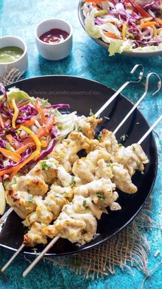 chicken skewers with coleslaw and slaw on a black plate