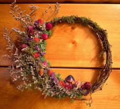 a wreath made out of branches and flowers on a wooden surface with other items around it